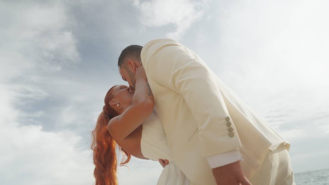 Beso de los novios bajo un cielo nublado