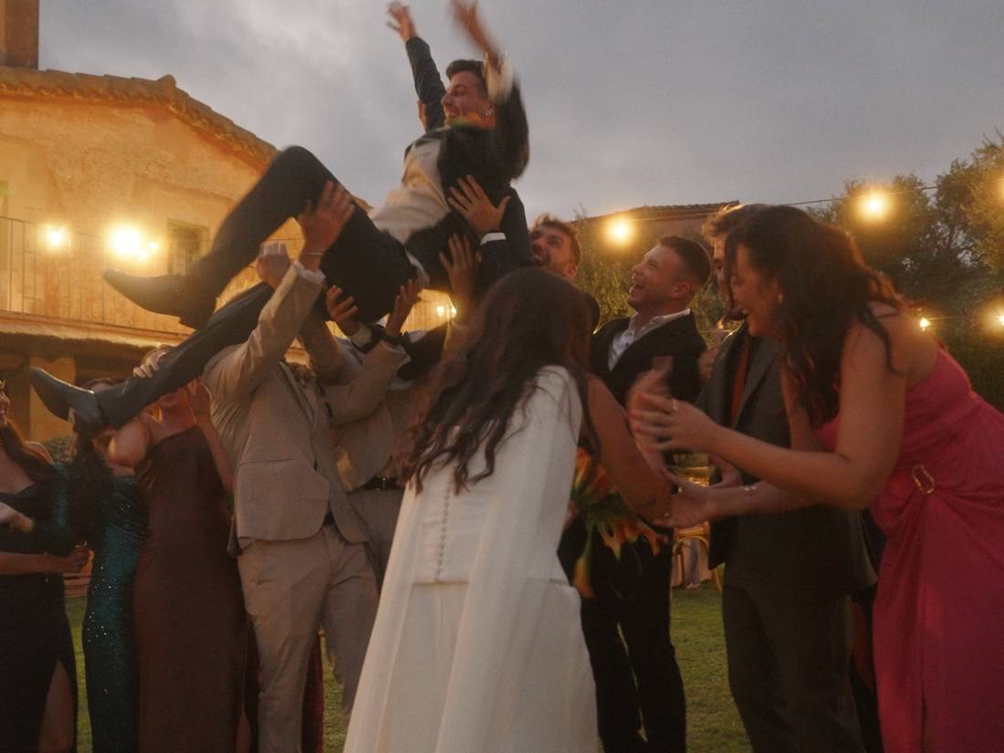 Los invitados mantean al novio al atardecer
